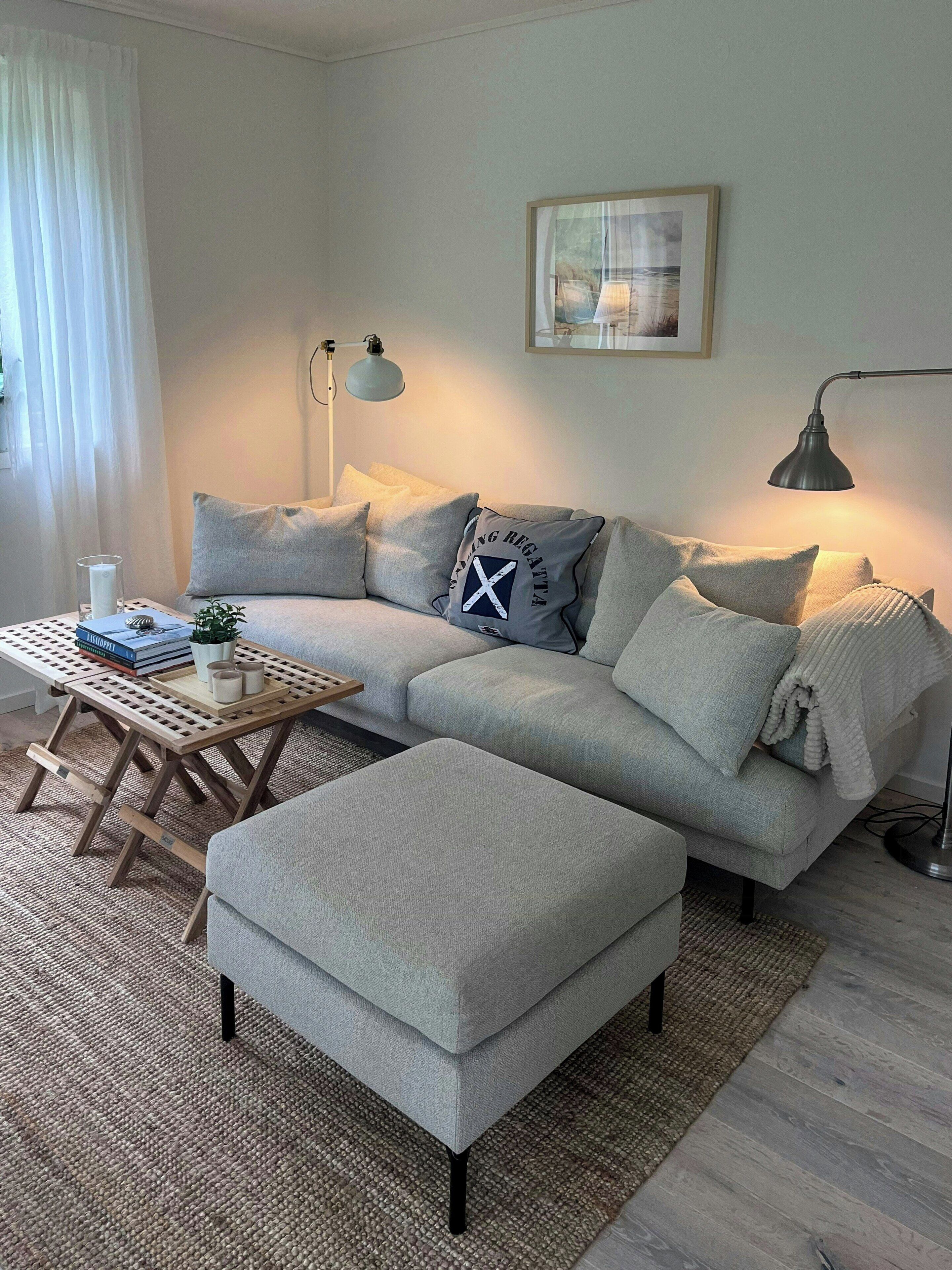 A modern living room with a grey sofa, a wooden coffee table, and a grey ottoman.