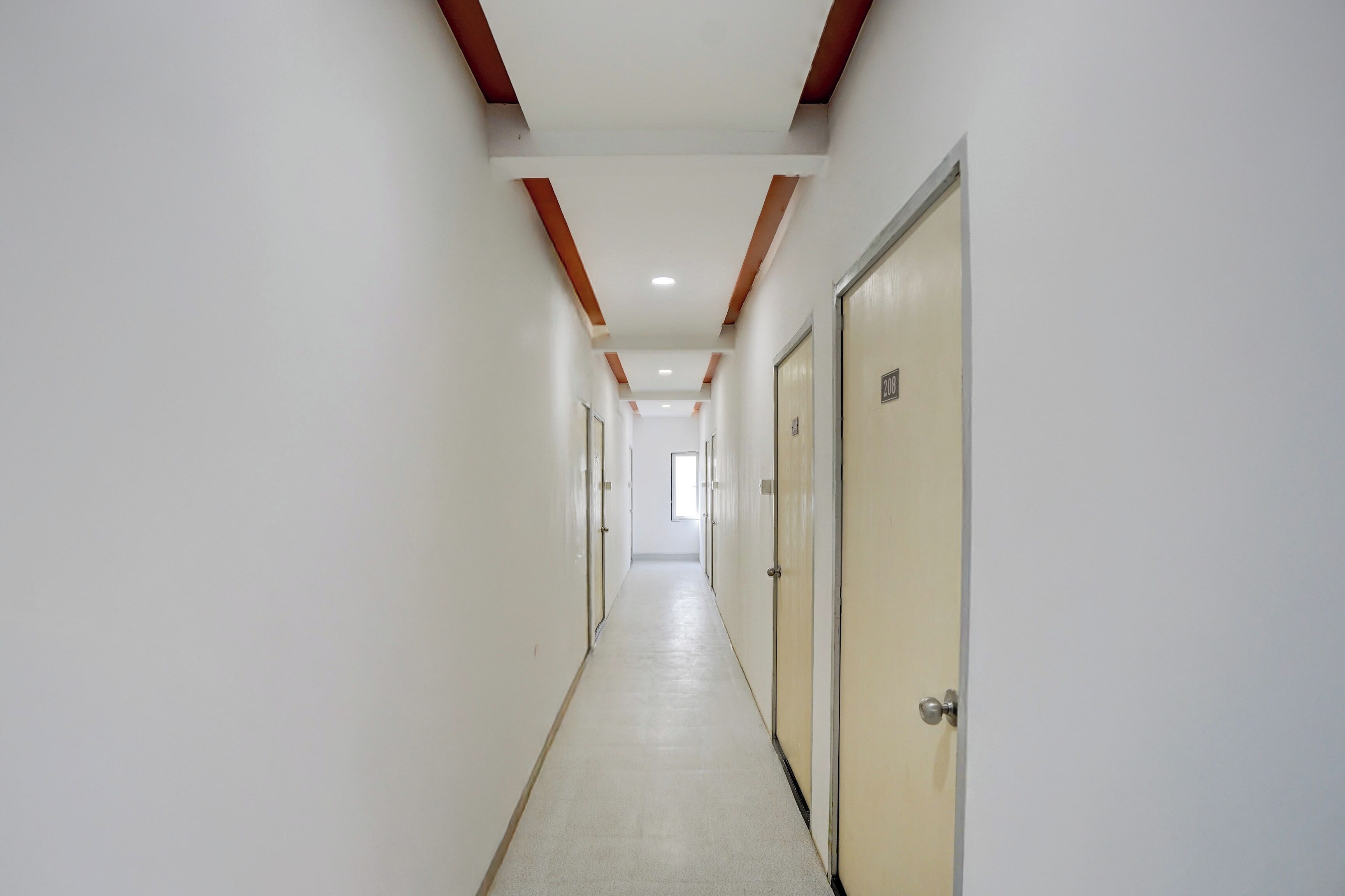 Un pasillo largo y estrecho con puertas a un lado y una pared lisa al otro.