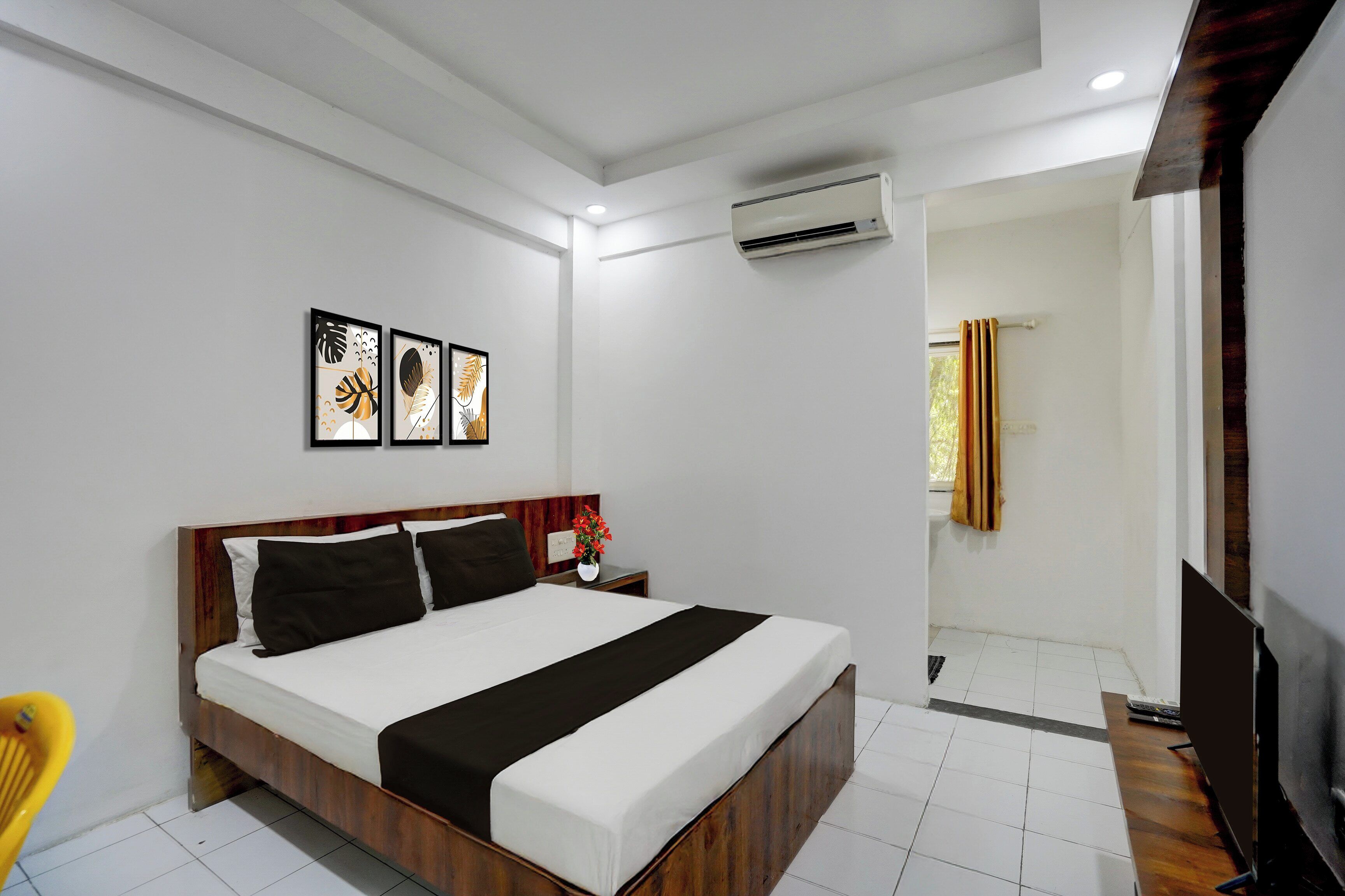 A hotel room with a bed, bedside table, and artwork on the wall.