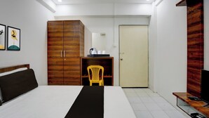 Habitación de hotel con cama, armario, escritorio con silla, televisor y puerta.
