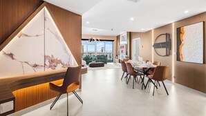 A modern dining area with a marble accent wall, a dining table set for six, and a view of the cityscape through large windows. - StayShort - Luxury 2BR with Marina Views | Sleeps 4 (Dubai)