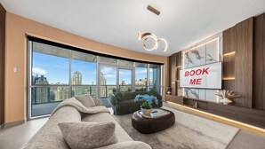 A modern living room with a large sofa, a coffee table, and a TV mounted on the wall. - StayShort - Luxury 2BR with Marina Views | Sleeps 4 (Dubai)