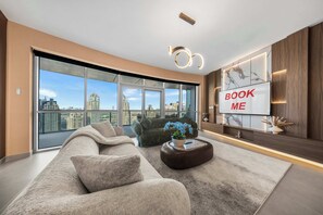 A modern living room with a large sofa, a coffee table, and a TV mounted on the wall. - StayShort - Luxury 2BR with Marina Views | Sleeps 4 (Dubai)