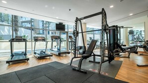 A modern gym with treadmills, weight machines, and a TV screen. - StayShort - Luxury 2BR with Marina Views | Sleeps 4 (Dubai)