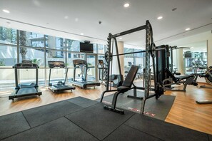 A modern gym with treadmills, weight machines, and a TV screen. - StayShort - Luxury 2BR with Marina Views | Sleeps 4 (Dubai)