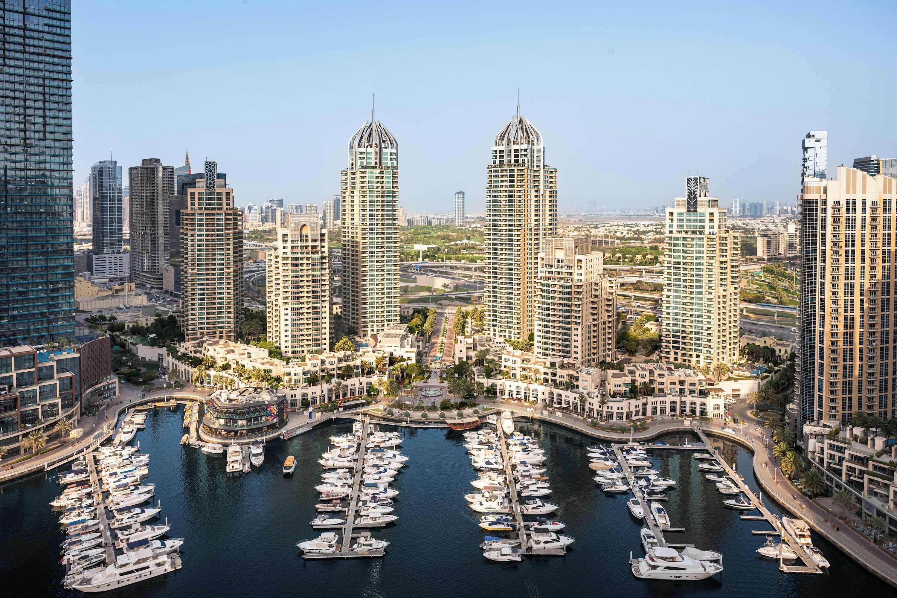A marina with numerous boats docked, surrounded by high-rise residential buildings.