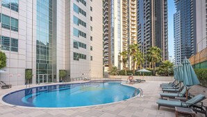 A swimming pool with lounge chairs and umbrellas, surrounded by high-rise buildings. - StayShort - Luxury 2BR with Marina Views | Sleeps 4 (Dubai)