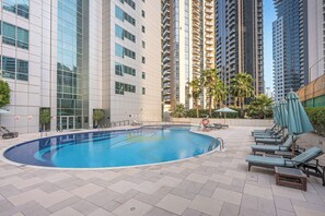 A swimming pool with lounge chairs and umbrellas, surrounded by high-rise buildings. - StayShort - Luxury 2BR with Marina Views | Sleeps 4 (Dubai)