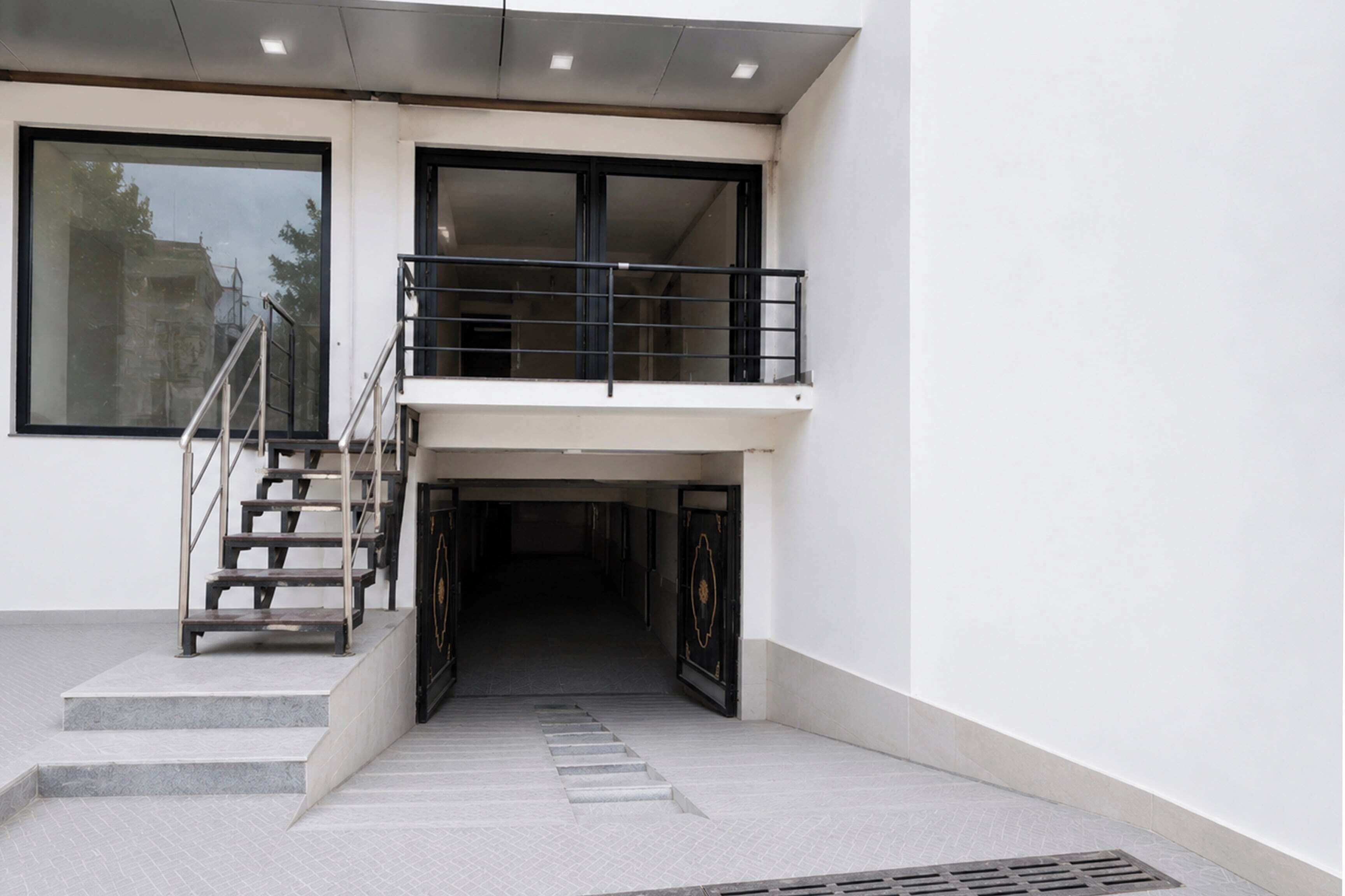 A modern building entrance with a staircase leading to a balcony.