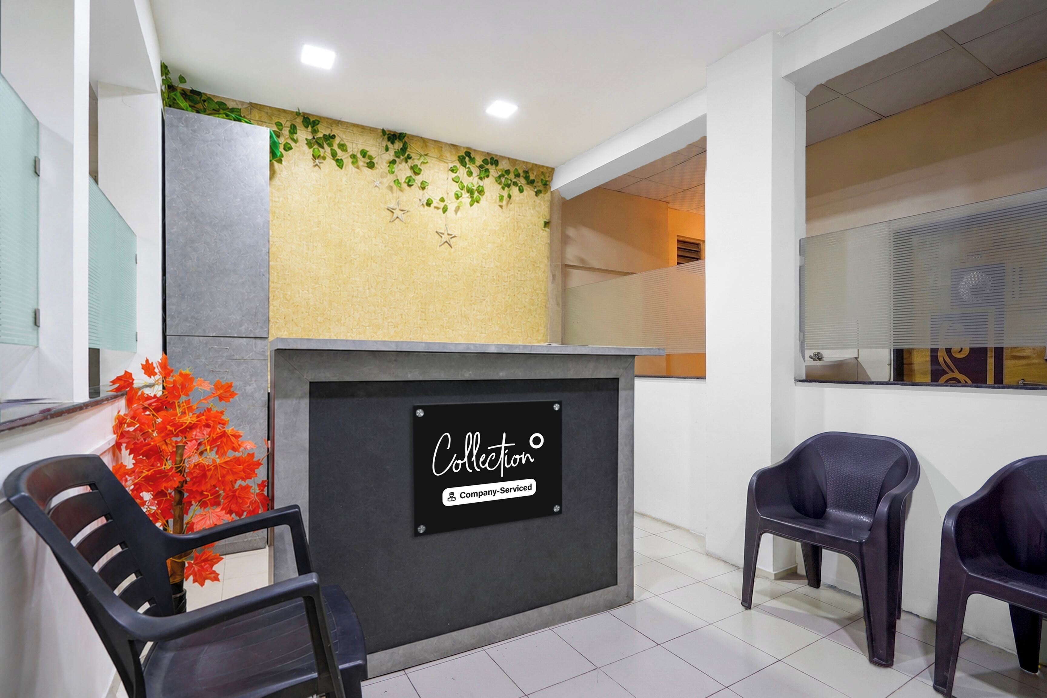 A reception area with a sign indicating it's a company-serviced collection point. There are two chairs and a plant with red leaves.