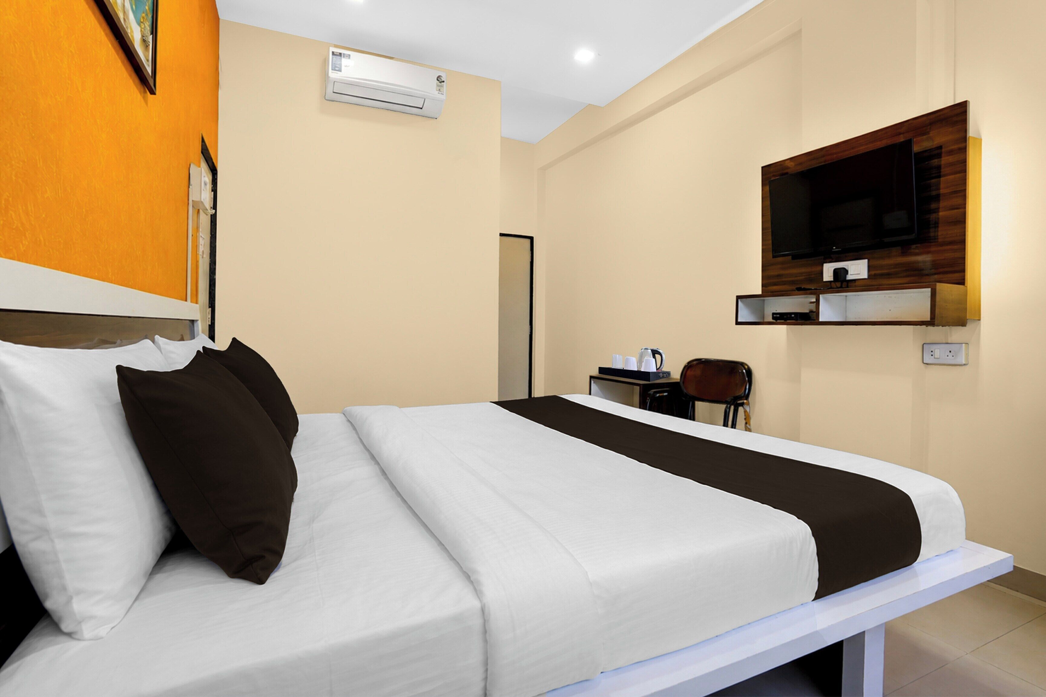 A hotel room with a bed, a television mounted on the wall, and a coffee maker on a small table.