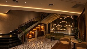 A modern lobby with a geometric patterned floor, a staircase, and a seating area with a fireplace. - Grand Unicorn Club (Islamabad)