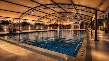 Piscina interior con zona techada, pared de piedra y servicios junto a la piscina.