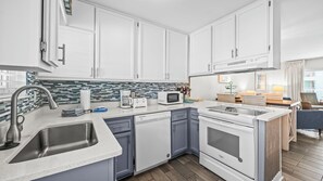 A modern kitchen with white cabinets, a stainless steel sink, a microwave, and a stove. - 2BR Gulf-side condo w private beach access & heated pool (Gulf Shores)