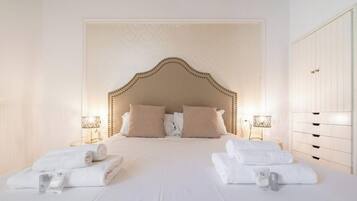 Una camera d'albergo con un letto grande, due lampade ai comodini, un armadio e asciugamani piegati con cura.
