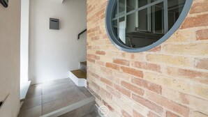 A staircase with a brick wall and a round window. - Estay - The Corner House Cagliari Room 2 (Cagliari)