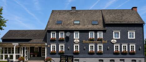 Un bâtiment traditionnel à la façade sombre, doté de nombreuses fenêtres et d’une enseigne indiquant « Dahlbrucker Hof ».
