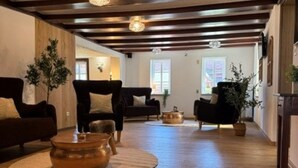 Un salón espacioso con suelo de madera, sofás oscuros y una mesa de centro.