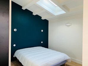 A bedroom with a bed, a skylight, and a wall with circular cutouts. - Village house 300 meters from the beach.  Pets are allowed. (Sainte-Marie-de-Ré)