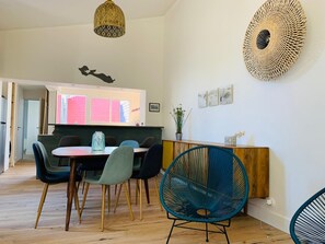 A dining area with a wooden table, multiple chairs, and a hanging light fixture. - Village house 300 meters from the beach.  Pets are allowed. (Sainte-Marie-de-Ré)