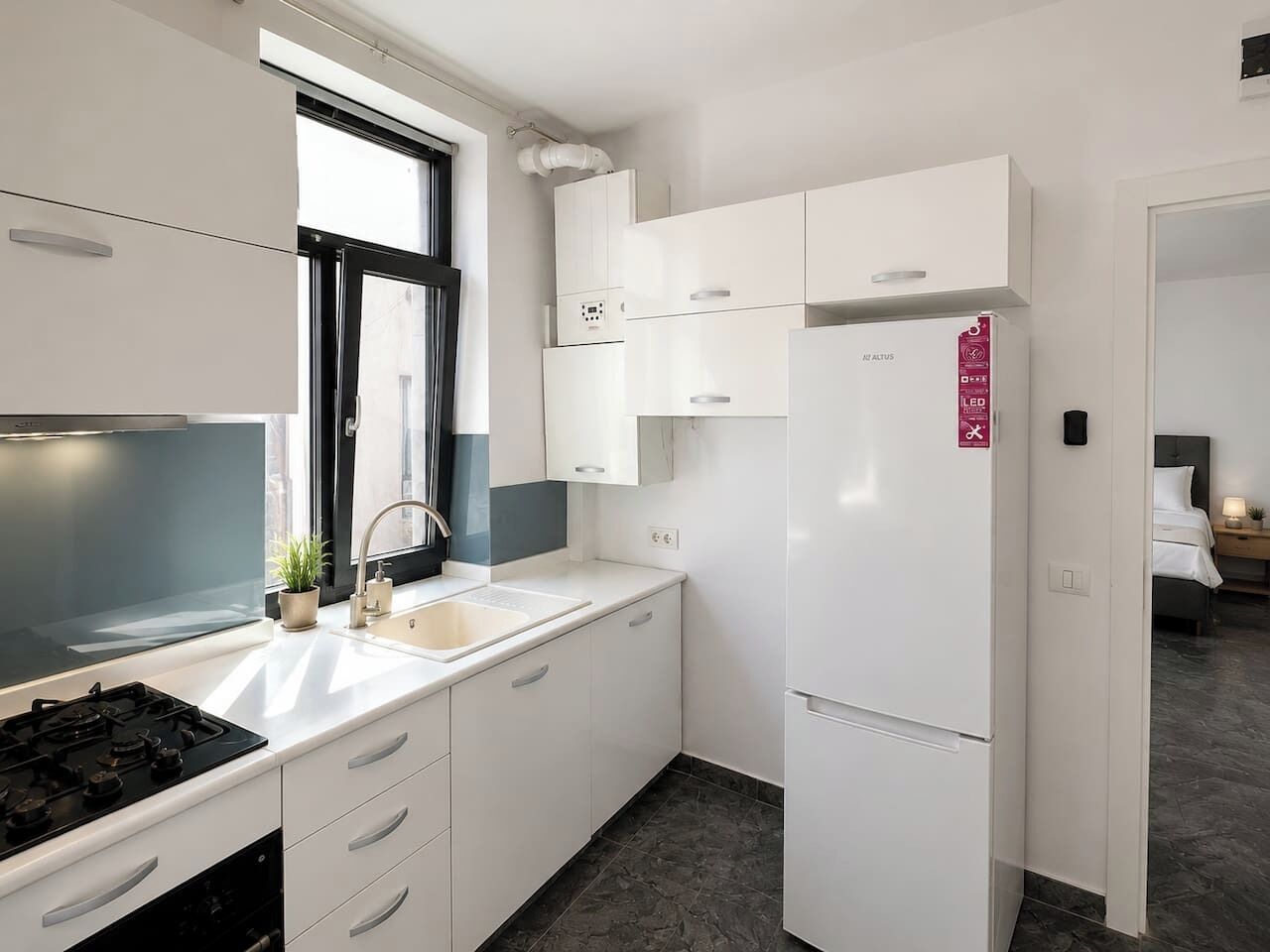 Eine moderne Küche mit weißen Schränken, einem eingebauten Herd und einem Kühlschrank.