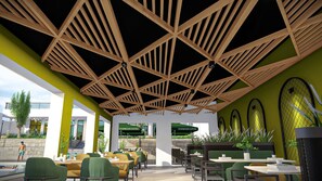 An outdoor café with wooden ceiling beams, green seating, and plants. - Pacific Hotel (Kigali)