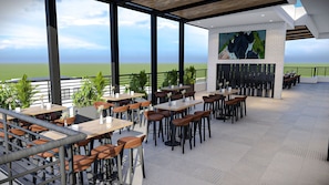 Un área de comedor al aire libre con mesas y sillas, vista al mar y un diseño arquitectónico moderno.