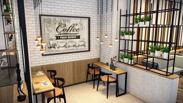 A cafe interior with brick walls, a framed coffee sign, wooden tables, chairs, hanging pendant lights, and a plant display.