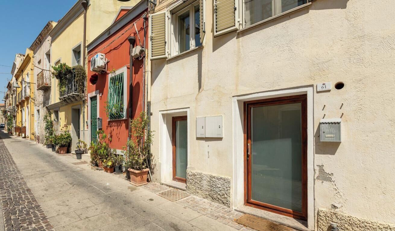 Filera d'edificis amb balcons, plantes en testos i un carrer pavimentat amb llambordes.