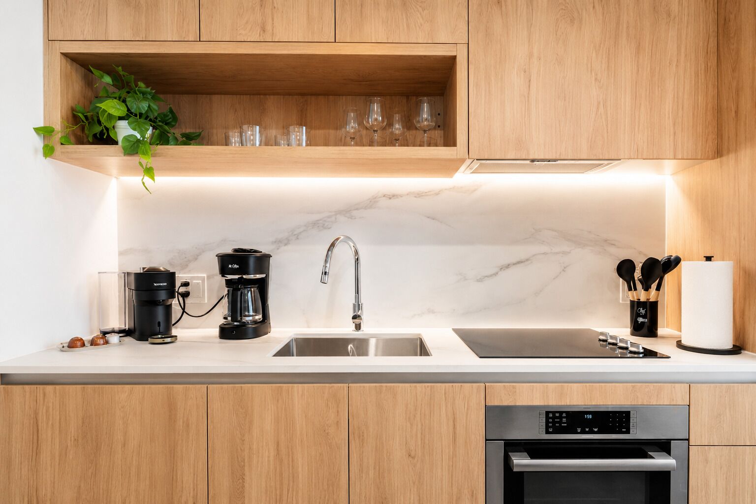 A modern kitchen with wooden cabinets, a marble backsplash, a coffee maker, a sink, and a dishwasher.