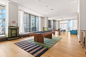 Un salon moderne avec une table de billard, de grandes fenêtres et une vue sur le paysage urbain.