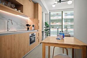 A modern kitchen with wooden cabinets, a built-in oven, and a sink. - The Crosby (Miami)