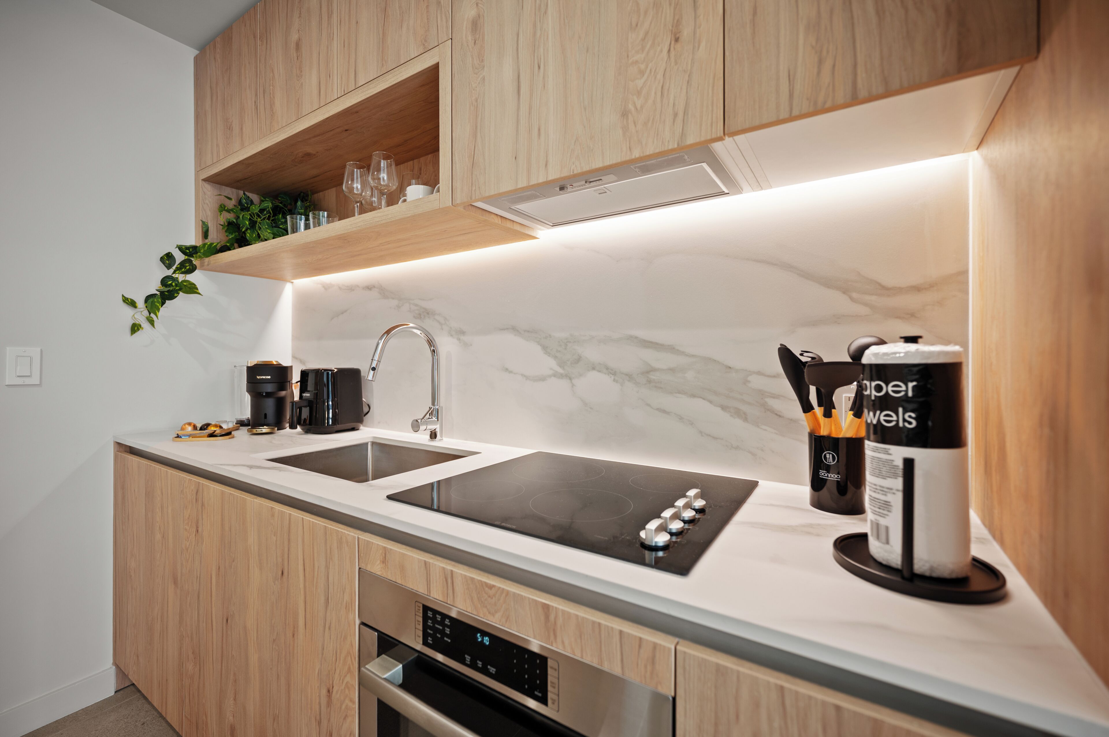 A modern kitchen with a double sink, stainless steel appliances, and wooden cabinetry.