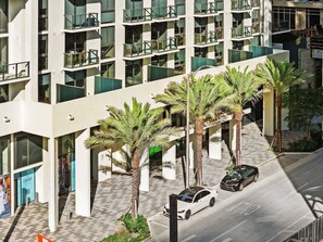 A multi-story hotel with balconies, palm trees, and a parking area. - The Crosby (Miami)