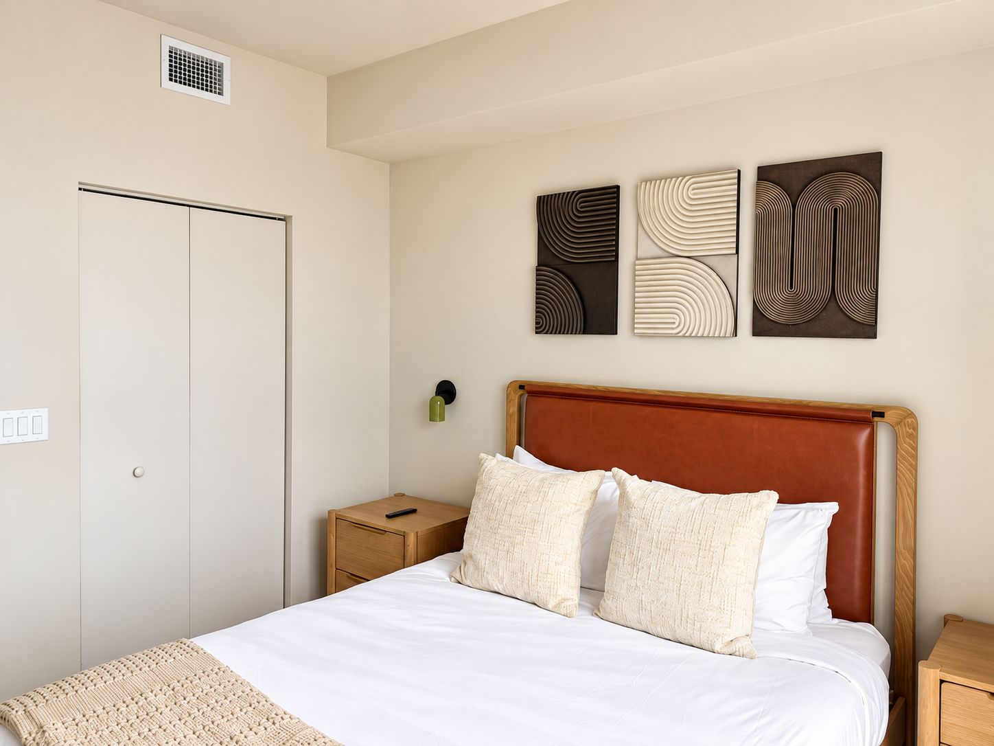 Ein Hotelzimmer mit Bett, Nachttisch, Wandlampe und Kunstwerk.