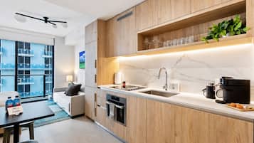 Une cuisine moderne avec des meubles en bois, un plan de travail en marbre, un four encastré et une machine à café.