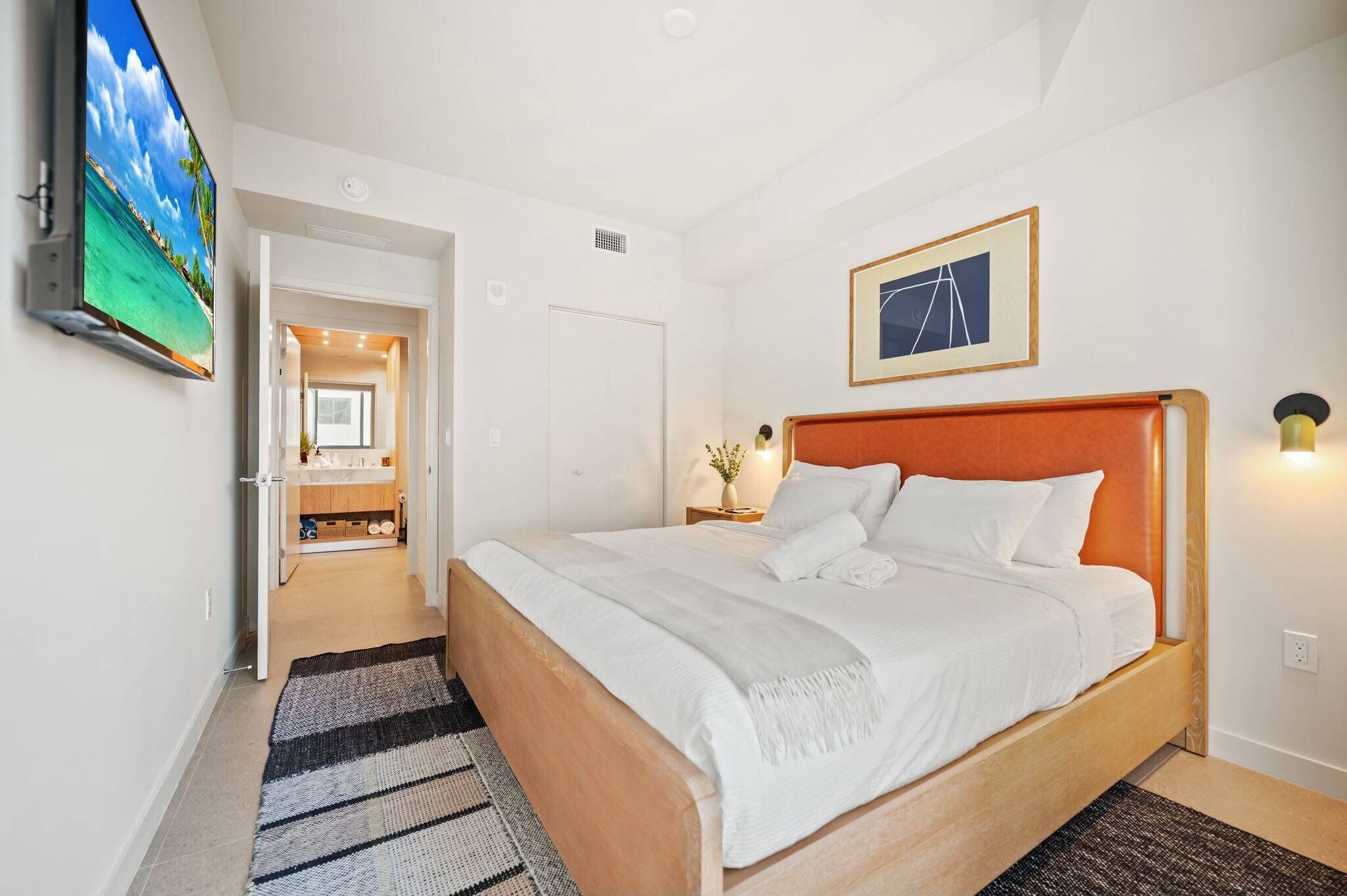 Een hotelkamer met een bed, een televisie, een ingelijst schilderij en een badkamer door een open deur zichtbaar.