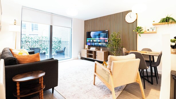 Uma sala de estar moderna com um sofá, uma mesa de centro, uma televisão e um espaço de jantar com cadeiras e uma mesa.