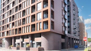 Um edifício de vários andares com design arquitetônico moderno, com uma série de varandas e grandes janelas.