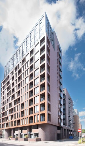 Ein mehrstöckiges Gebäude mit zeitgemäßer Architektur, das eine Reihe von Balkonen und große Fenster aufweist.