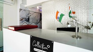 A reception desk with a marble backsplash, a flag display, and a sign reading 'Collection & Company Services'. - Collection O Goregaon Near Film City (Mumbai)