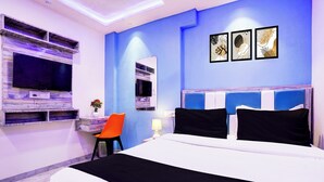 A modern hotel room with a large bed, a flat-screen TV, a small table with a plant, and a chair. - Collection O Goregaon Near Film City (Mumbai)