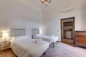 A hotel room with two beds, a wooden dresser, a mirror, and an air conditioning unit. - Ginori 3 G in Firenze (Florence)