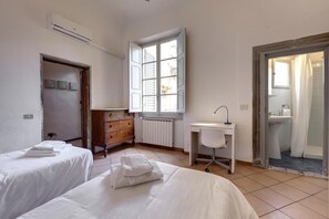 A bedroom with two beds, a desk, a radiator, and a window. - Ginori 3 G in Firenze (Florence)