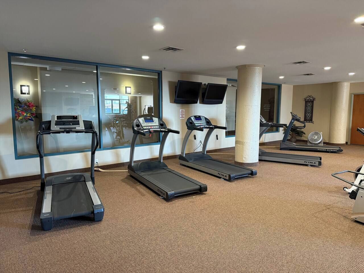 Ein Fitnessraum mit Laufbändern, einem Ergometer und einem Rudergerät.