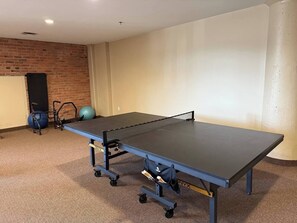 Ein Tischtennis-Tisch in einem Raum mit Backsteinwand und Teppichboden.
