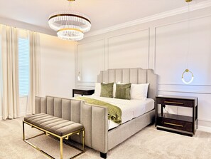 A bedroom with a bed, bench, nightstands, and a chandelier. - Spacious and Modern Retreat w/ Pool & Spa, Walk to Clubhouse (Kissimmee)