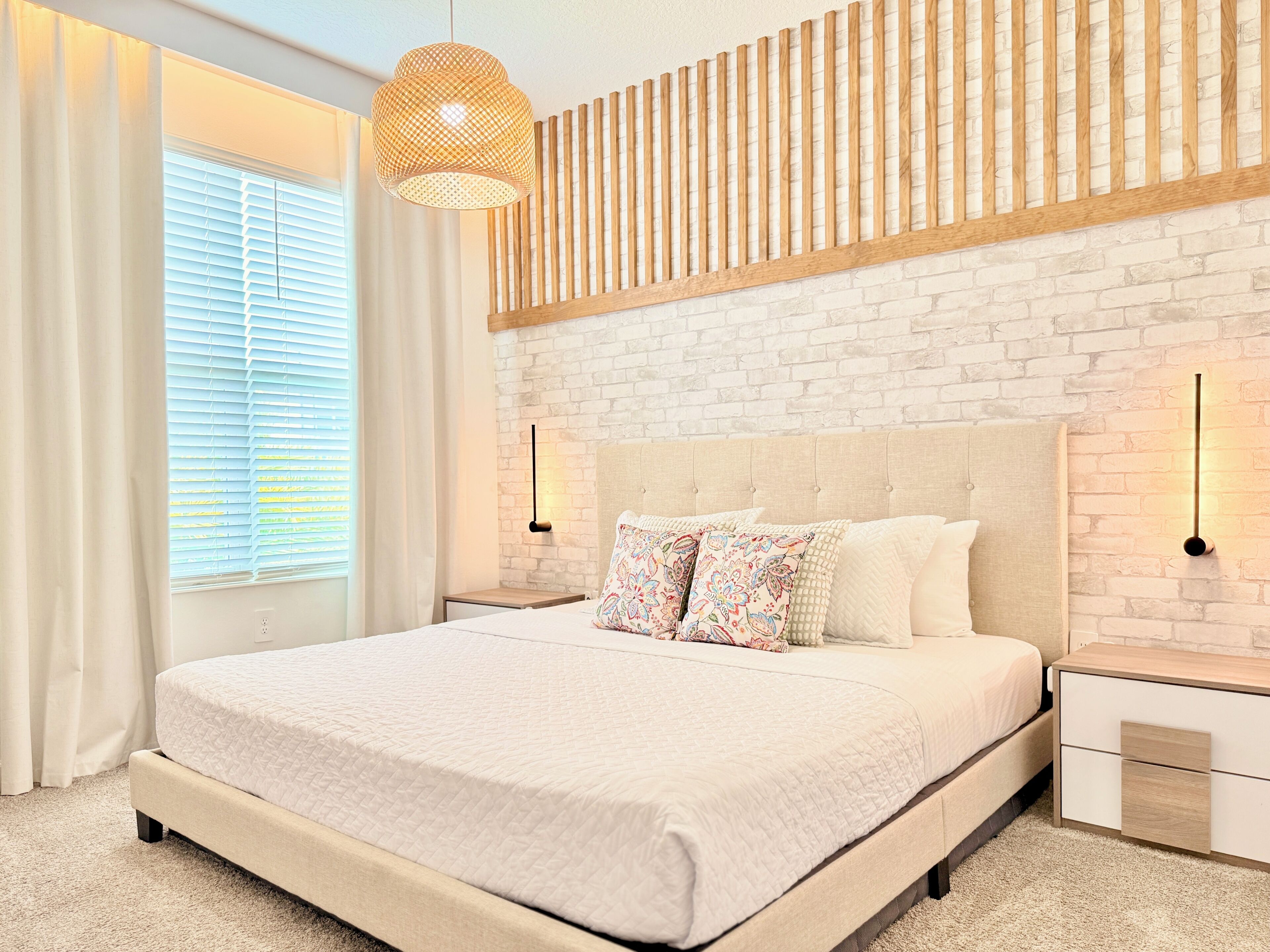 A modern bedroom with a large bed, a wooden slat wall, and a hanging light fixture.