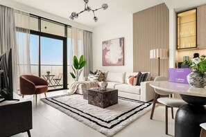 A modern living room with a sofa, coffee table, and a dining area with a table and chairs. - Silkhaus Premium 2BR in Golf Grand Dubai Hills (Dubai)