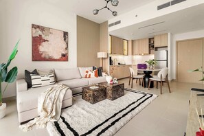 A modern living room with a sofa, coffee table, and a large abstract painting. - Silkhaus Premium 2BR in Golf Grand Dubai Hills (Dubai)